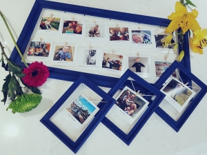 Blue Photo frames with pictures pegged. Flowers by the side